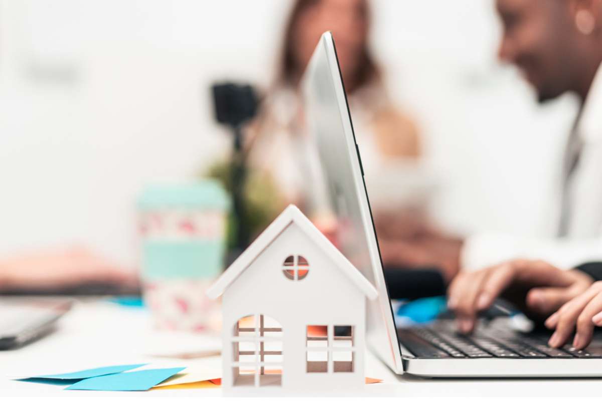 A laptop next to a small house model. Using a content marketing agency can help drive more property management leads