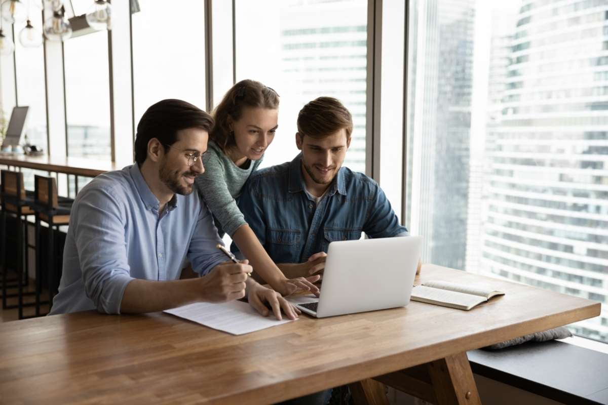 Creative business team sharing laptop in office, watching startup presentation